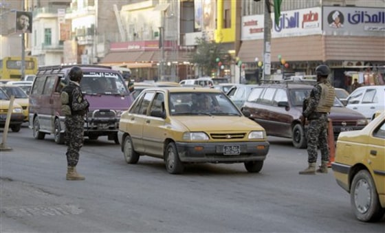 Iraqi policemen stand guard as hundreds of vehicles wait to be searched at a checkpoint in Baghdad, Iraq, on Tuesday.